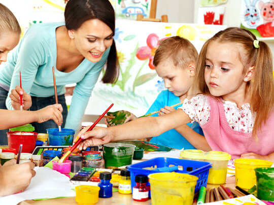 A woman and two children painting with paint.