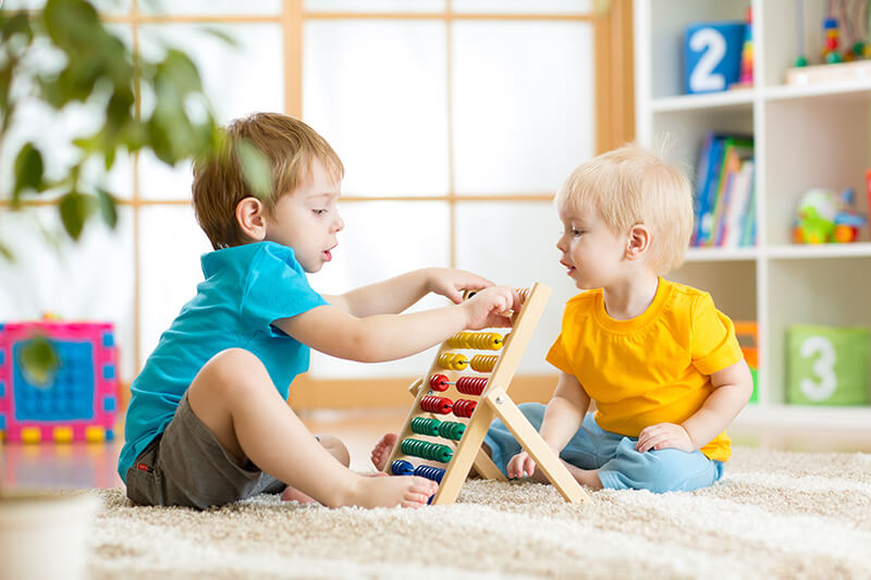 Two young children playing with a toy on the floor.