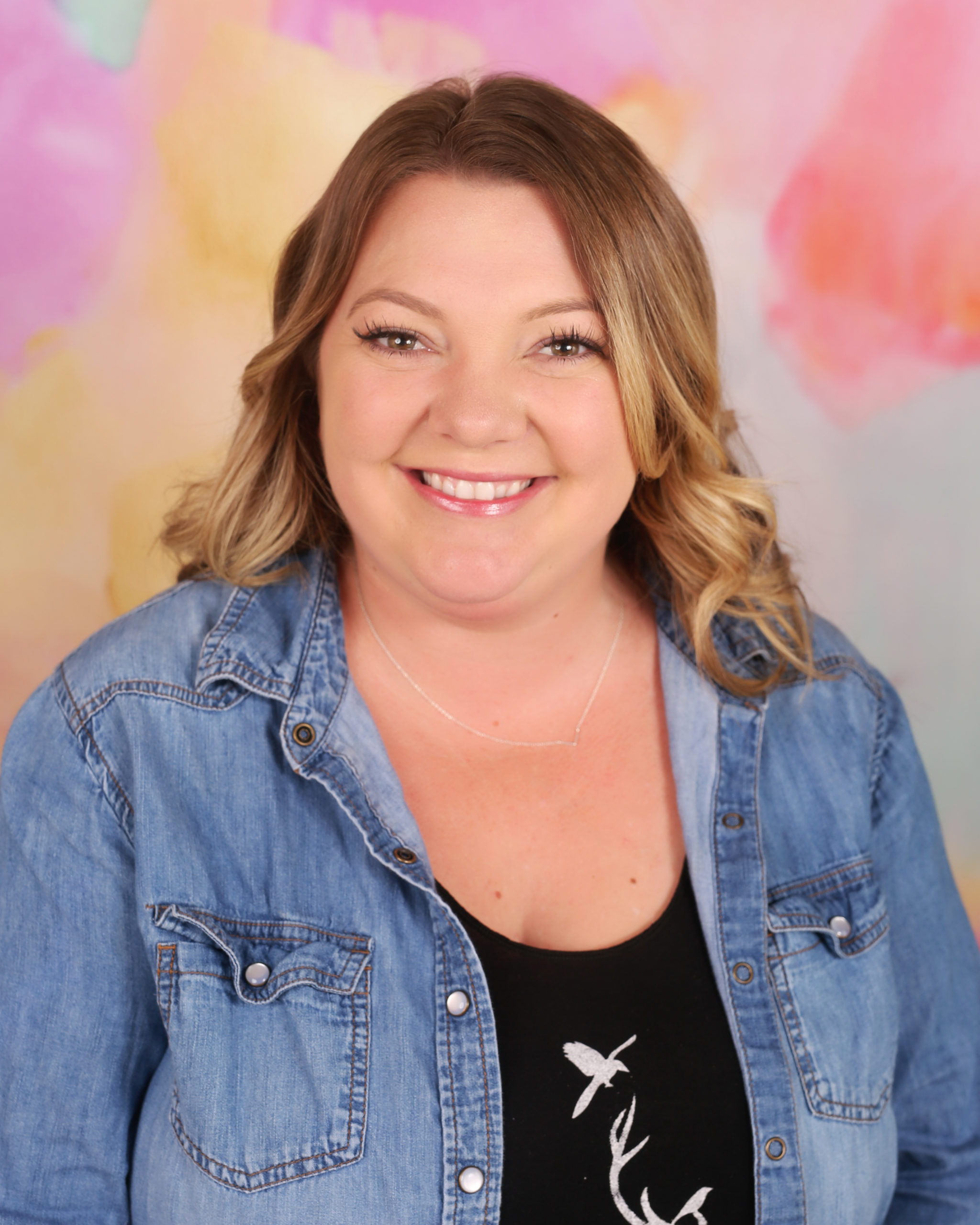 A woman in a jean jacket smiling for the camera.