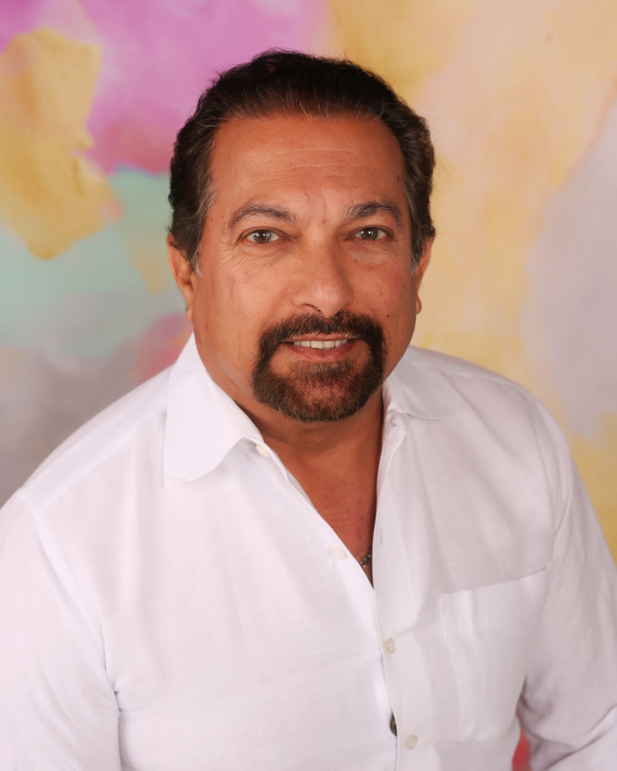 A man with beard and mustache wearing white shirt.