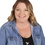 A woman in a jean jacket smiling for the camera.